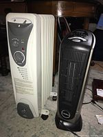 Side view of the oil-filled radiator heater next to the black Lasko ceramic tower heater to show both items in the lot.