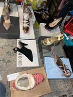Multiple pairs of ladies shoes in worn condition displayed on shoe boxes, including various styles and colors.