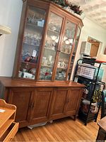 Full view of two-piece china cabinet showing glass hutch on wooden base with contents inside.