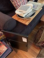 Black foldable lap desks leaning against a sofa with a lot number tag 427 visible on each.
