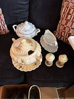 Overview of cream-colored soup tureen with floral design, matching salt and pepper shakers, white Haviland gravy boat, and white covered dish