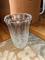 Clear glass vase with scalloped rim on carpet with cardboard box background.