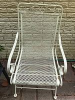 Front view of the wrought iron rocking chair showing the mesh seat and backrest with scroll design and curved armrests.