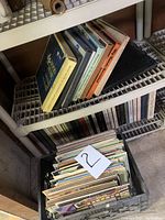 Crate of vinyl records albums with some on a shelf above showing various colors and album titles such as "Mister Rogers" in the crate.