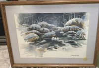 Framed watercolor landscape with snow-covered rocks and trees with signature.