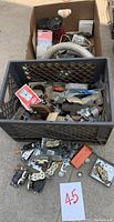Two crates containing assorted electrical parts including plugs, metal outlet boxes, various outlet covers, and mounting hardware.