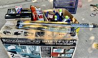 Wide view of lot showing box of Chamberlain 1/2 HP garage door opener, Goodyear wiper blades, automotive fluids, and miscellaneous auto supplies.