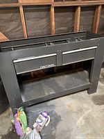 Gray Craftsman metal stand with two drawers and pegboard side panel showing holes for accessories