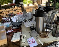 Overview of various kitchen appliances including coffee makers, blenders, and utensils on a table.