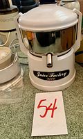 White and chrome electric Juice Factory 2000 juicer with spout and lid on countertop.