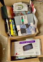 Overview of all items in cardboard box, including Zenith video rewinder, mixed media formats and cases.
