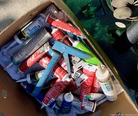 Box of multiple tubes of used caulking and a blue caulking gun applicator all used, inside a cardboard box