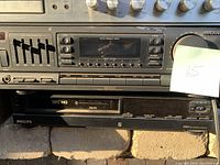 Photo showing Magnavox tuner, Philips VHS player, and part of vintage stereo equipment with multiple knobs and sliders