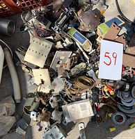 Overhead photo showing a large assortment of used electrical parts including outlet covers, wires, brackets, and other hardware.