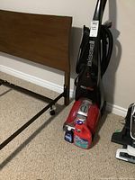 Front view of Bissell ProHeat upright carpet cleaner with the cleaning solution bottles placed at the base.