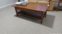 Front angle view of wood coffee table with plates and bowls on top, showing the table's finish and style.