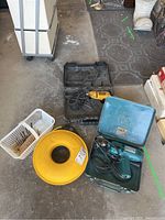 Overview of the drills, extension cord winder, and drill bits in a garage setting.