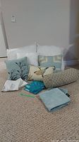 Overview of all pillows and pillow covers on carpet showing decorative patterns and colors.