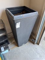 Tall black rectangular Veradek planter with soil inside, shown from a slight angle highlighting overall shape and dirt presence.