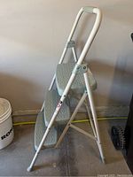 Side view of the fully opened three-tier StepRight folding ladder in grey with rubber feet and cushioned handle.