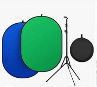 Double-sided collapsible backdrop with green and blue fabric, tripod stand set up, and carrying bag laid out.