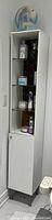 Front view of the white IKEA bathroom display cabinet showing shelves and cupboard door.