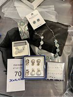 Photo of jewelry lot showing silver-tone floral necklace, wide silver-tone bangle with turquoise stones, six pairs of clip-on earrings in a box, pack of assorted stud earrings, and a pair of turquoise floral earrings on Reflections card.