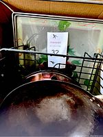 Close-up of wok showing seasoned surface and part of wok stand and drying rack.