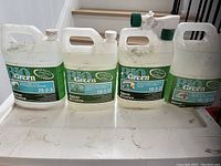 Four large white plastic containers of Bio Green liquid lawn food with different nutrient ratios on labels.