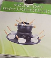 Photo showing boxed 20-piece fondue set with black pot, white bowls, and wooden-handled forks.