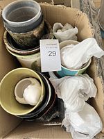 Boxes containing various sizes of used ceramic and stoneware pots and vases, some wrapped in packing material.