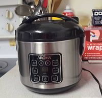 Aroma digital rice cooker with stainless steel shell and black lid, front control panel visible