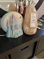 Both Himalayan salt lamp and castle night light shown together on surface with visible tag on salt lamp