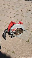 Red Skil circular saw on pavement showing motor and blade guard