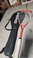 Orange and black Head Titanium squash racket with white grip, in carrying case.