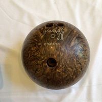 Top view of brown marbled Galaxy 300 bowling ball with three finger holes showing engraved brand and serial number.