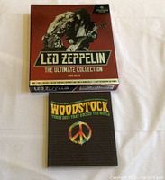 Photo showing the Led Zeppelin The Ultimate Collection box set and Woodstock book on a white background.