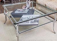 Rectangular glass coffee table with clear glass top and metal frame with curved legs. Lower shelf is tinted glass. Visible scratches on glass.