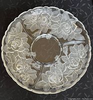 Top-down view of a round glass plate divided into four sections with embossed floral rose patterns