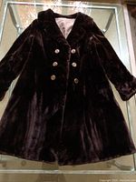 Full view of the dark brown vintage real fur coat laid flat to show overall condition and style including metal buttons and double-breasted front.