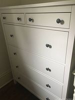 Front view of white IKEA 6-drawer chest with black round knobs