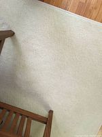 Beige carpet on hardwood floor showing texture and some indentations from furniture.
