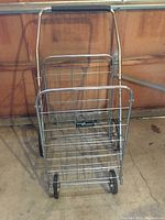 Front angled view of Easy Wheels steel shopping cart showing structure, wheels, and handlebar.