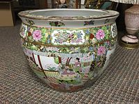 Full view of the round, wide ceramic pot decorated with handpainted Chinese traditional scenes and floral designs.