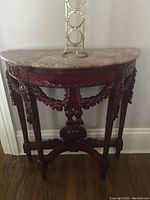 Ornate dark wood console table with pink marble top and carved decorations visible.