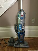Full frontal view of Hoover Air Cordless Lift vacuum with charger on hardwood floor.