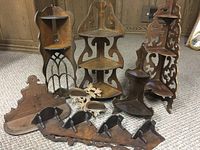 Full lot of seven antique wooden corner wall hanging shelves arranged on carpet with wood panel background.