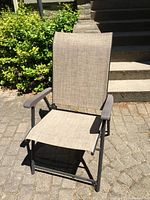 Full view of the foldable outdoor chair showing the fabric seat and backrest, armrests, and metal frame.