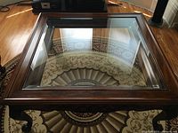 Top view showing the glass inset top and wooden frame of the square coffee table.