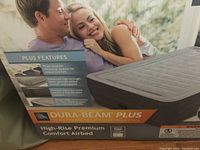 Box front showing a couple lying on an Intex Dura-Beam Plus air bed with plus features and product info.